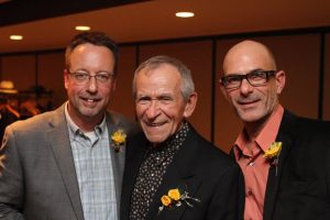 Pete Samek, AIFD, left, and James Lutke, right, celebrate with Friese. 