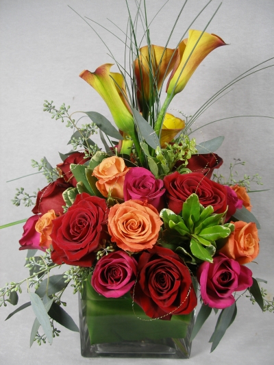 Square vase with red roses, orange roses, hot pink and mango mini-callas